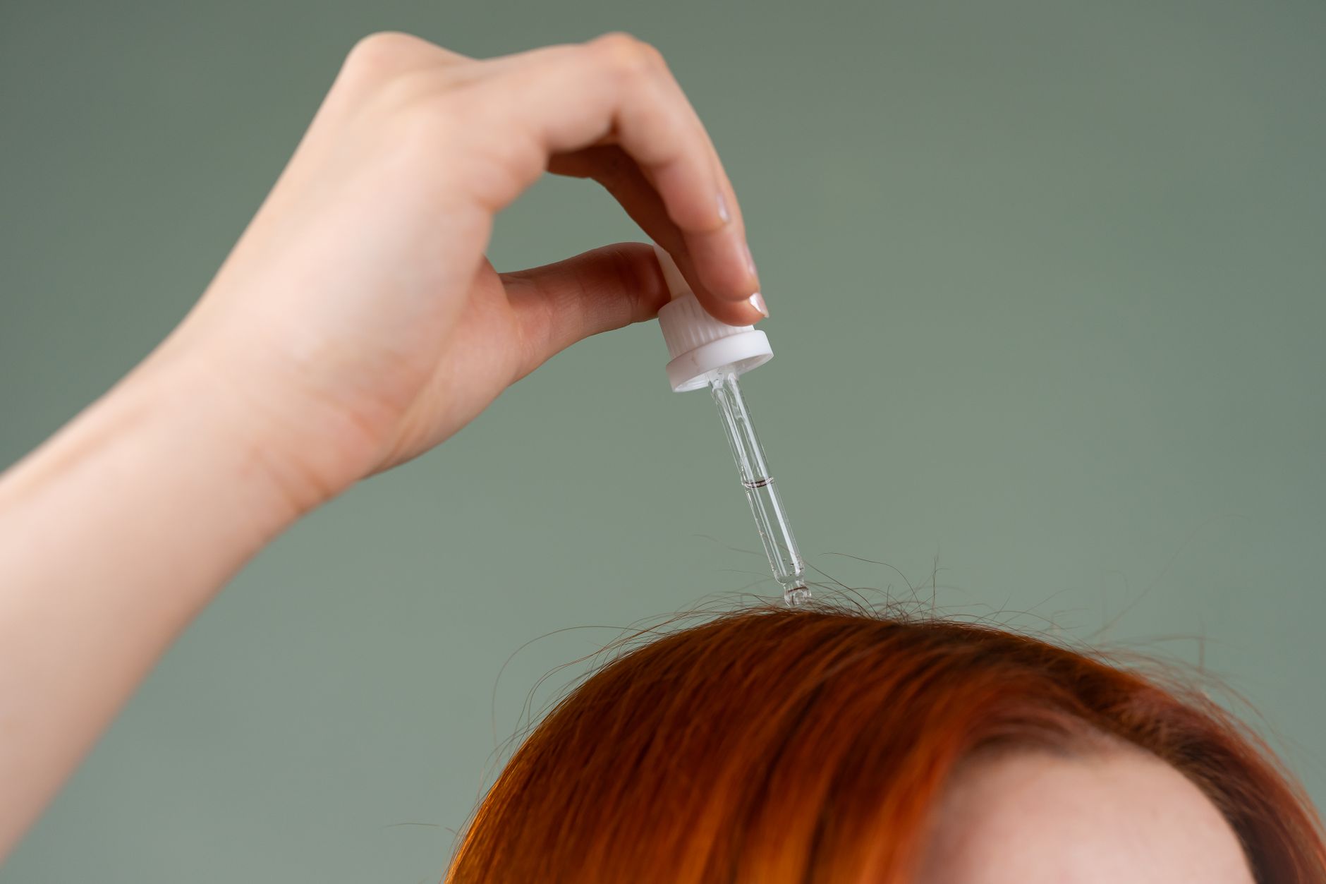 Applying hair treatment serum to scalp roots with a dropper